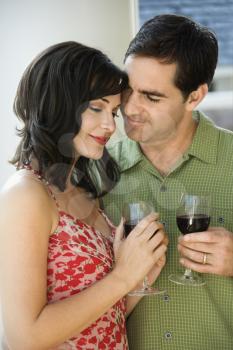 Man and woman act affectionately while holding red wine. Vertical shot.