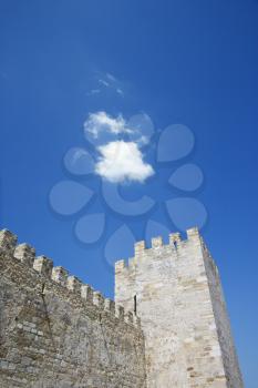 Low angle view of an ancient castle battlement and tower against a blue sky. Vertical shot.