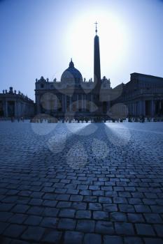 The east facade of St Peter's Basilica with the obelisk in the foreground. The sun is directly behind the obelisk. Vertical shot.