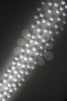 Overhead view of white round pills illuminated by a shaft of light. Vertical shot.