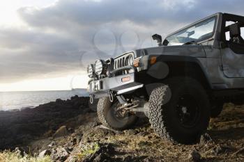 Low angle view of front of SUV on a rocky beach. Horizontal format.