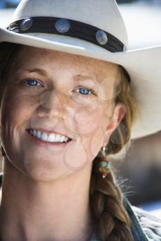 Attractive young woman smiling and wearing a cowboy hat. Vertical shot.