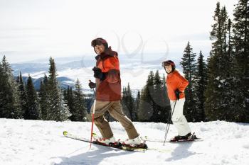 Side view of skiers on a snowy ski slope with trees and valley in background. Horizontal shot.
