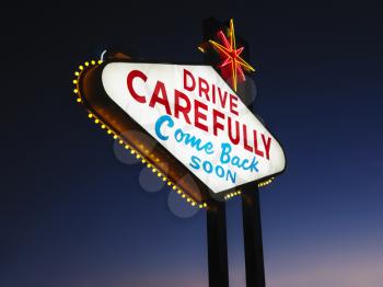 Las Vegas sign at night reading Drive carefully and Come back soon. Horizontally framed shot.