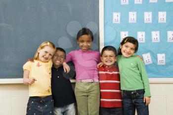 Group of diverse young students standing together in classroom. Horizontally framed shot.