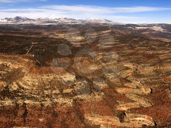 Aerial view of an arid, craggy landscape with mountains in the background. Horizontal shot.