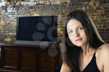 Portrait of pretty young Caucasian woman with television in background.