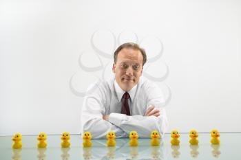 Portrait of middle aged  Caucasian businessman sitting at desk with ducks in a row.