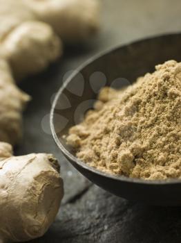 Royalty Free Photo of a Dish of Ginger Powder with Fresh Ginger Root