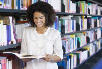 Royalty Free Photo of a Woman Reading a Book in a Library