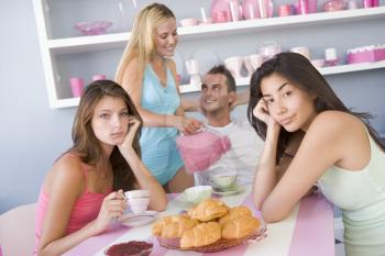 Royalty Free Photo of Women Looking Upset and Another Woman Pouring Tea for a Guy