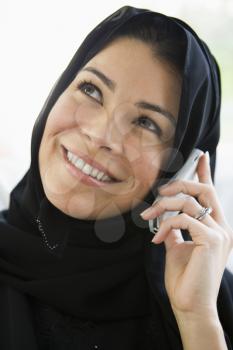 Woman indoors on cellular phone smiling (high key)