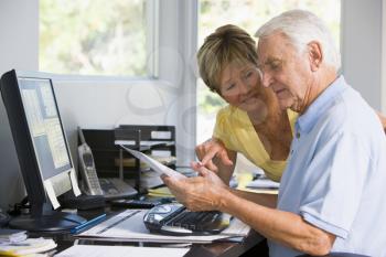 Royalty Free Photo of a Couple With Paperwork at the Computer