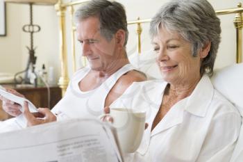 Royalty Free Photo of a Couple in Bed With the Newspaper and Coffee