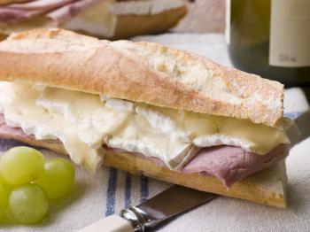 Royalty Free Photo of a Brie and Ham Baguette with White Wine and Grapes