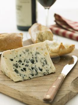Royalty Free Photo of a Wedge of Roquefort Cheese with Rustic Baguette and Red Wine