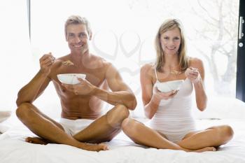 Royalty Free Photo of a Couple in Bed Eating Cereal