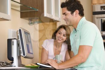 Royalty Free Photo of a Couple in the Kitchen With a Laptop