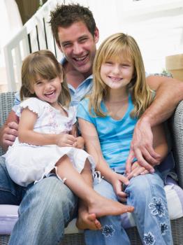 Royalty Free Photo of a Father and Two Daughters Sitting Outside