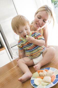 Royalty Free Photo of a Mother and Baby in a Kitchen Eating Healthy Food