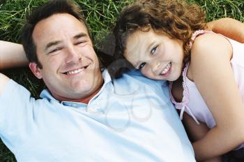 Royalty Free Photo of a Father and Daughter Lying on the Grass
