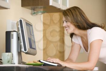 Royalty Free Photo of a Girl on a Computer in the Kitchen