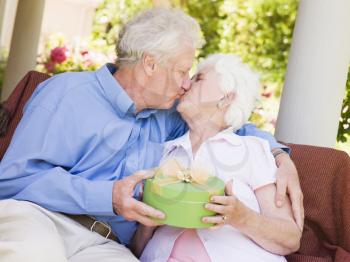 Royalty Free Photo of a Man Giving a Woman a Gift and Kissing Her