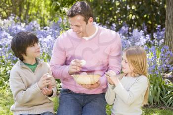 Royalty Free Photo of a Father Helping His Children Look for Easter Eggs