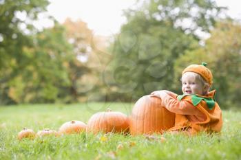 Royalty Free Photo of a Baby in a Pumpkin Costume With Pumpkins