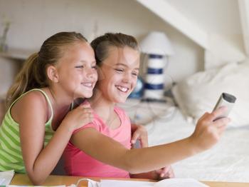 Royalty Free Photo of Two Girls Taking a Picture With a Cellphone