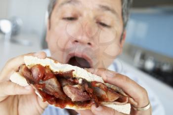 Royalty Free Photo of a Man Eating a Bacon Sandwich