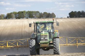 Royalty Free Photo of a Tractor Spraying a Field