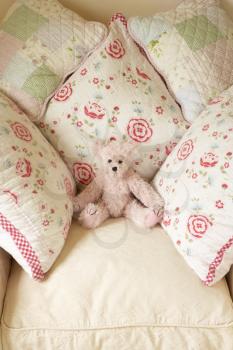 Royalty Free Photo of Pillows and a Teddy on a Chair
