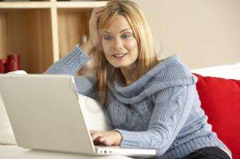 Young Woman Sitting On Sofa Using Laptop