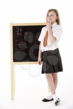 Thoughtful Female Student Wearing Uniform Next To Blackboard