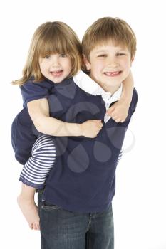 Studio Portrait Of Brother Giving Sister Piggy Back