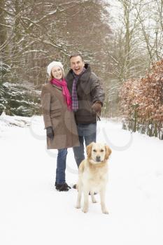 Senior Couple Walking Dog Through Snowy Woodland