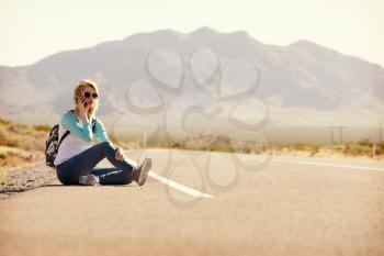 Woman On Vacation Hitchhiking Along Road Using Mobile Phone