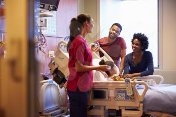 Pediatrician Visiting Parents And Child In Hospital Bed