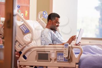 Male Patient In Hospital Bed Using Digital Tablet