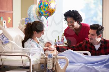 Family And Nurse With New Born Baby In Post Natal Department