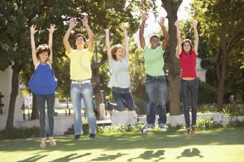 Group Of Teenagers Jumping In Air In Park