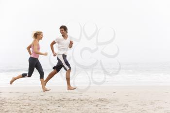 Young Couple Running Along Winter Beach