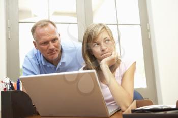 Angry Father And Teenage Daughter Using Laptop At Home