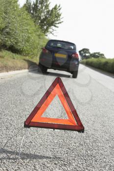 Car Broken Down On Country Road With Hazard Warning Sign In Foreground