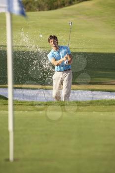 Male Golfer Playing Bunker Shot On Golf Course