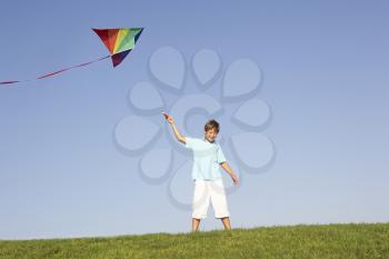 Young boy poses with kite in a field