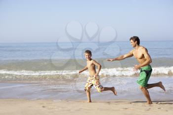 Father chasing young boy on beach
