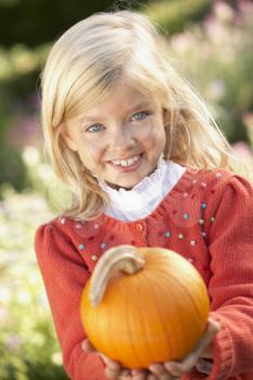 Young girl posing with pumpkin in garden