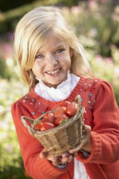 Young girl posing with tomatoes in garden